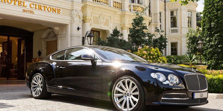 Voiture de luxe élégante garée devant un hôtel chic.